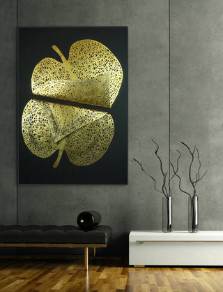 Golden dimensional leaf wall art displayed on a dark gray concrete wall above black and white furniture