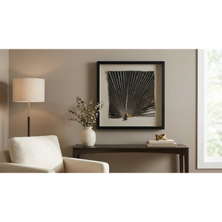 Living room with a white armchair, lamp, table with decor items, and framed artwork on the wall.